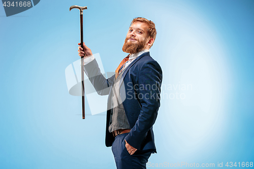 Image of The barded man in a suit holding cane.