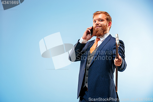 Image of The barded man in a suit holding cane.