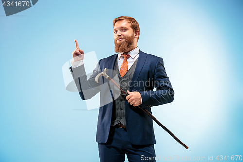 Image of The barded man in a suit holding cane.