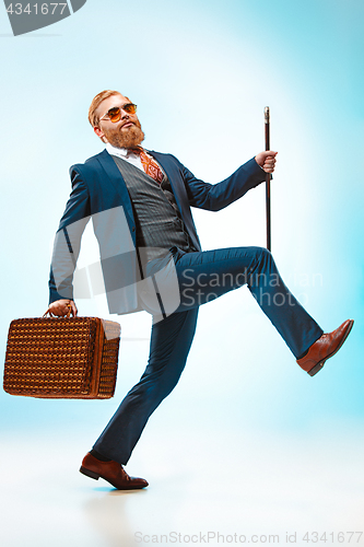 Image of The barded man in a suit holding cane.