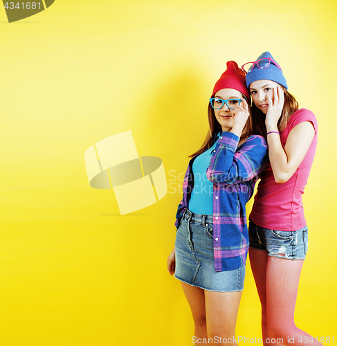 Image of lifestyle people concept: two pretty young school teenage girls having fun happy smiling on yellow background