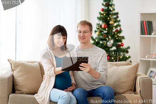 Image of man and pregnant wife with tablet pc at christmas