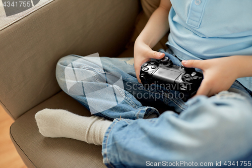Image of little boy with gamepad playing video game at home