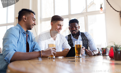 Image of male friends with tablet pc drinking beer at bar