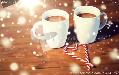 Image of christmas candy canes and cups on wooden table