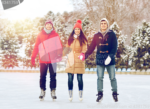 Image of happy friends ice skating on rink outdoors