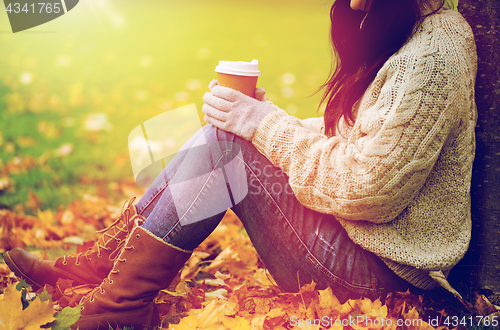 Image of close up of woman drinking coffee in autumn park