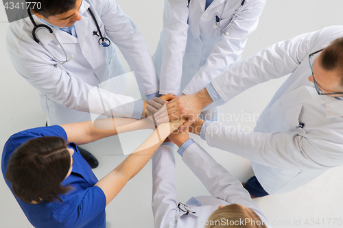 Image of group of doctors with hands together at hospital