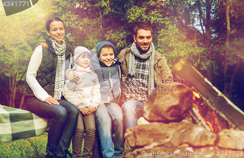 Image of happy family sitting on bench at camp fire