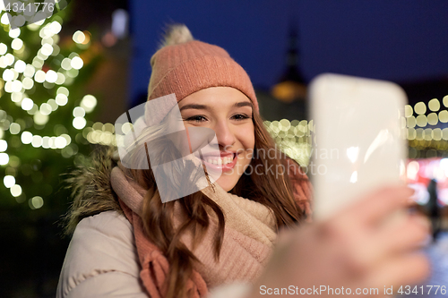 Image of young woman taking selfie over christmas tree
