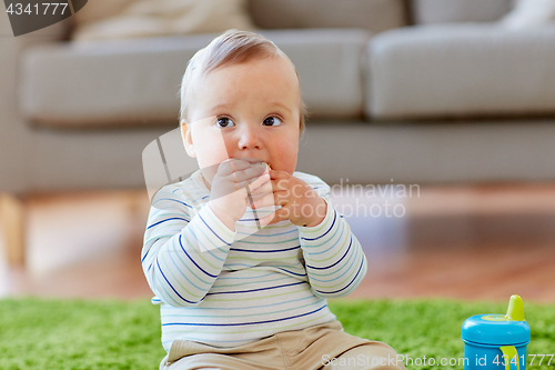 Image of baby boy on floor and eating rice cracker at home