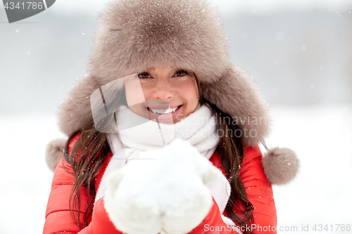 Image of happy woman with snow in winter fur hat outdoors