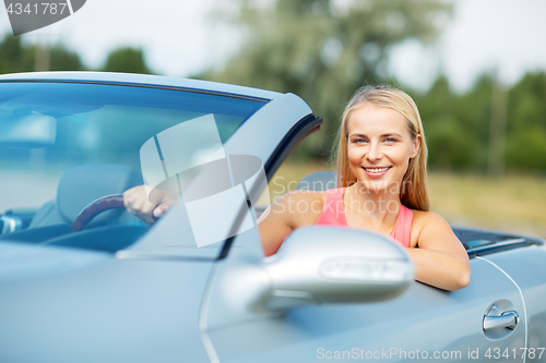 Image of happy young woman driving convertible car