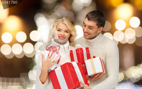 Image of happy couple in sweaters holding christmas gifts