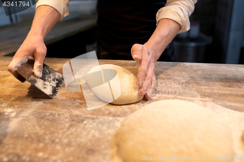 Image of baker portioning dough with bench cutter at bakery