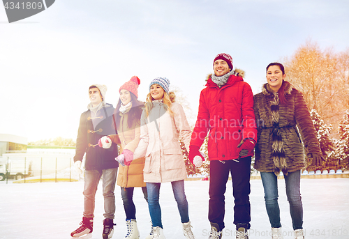 Image of happy friends ice skating on rink outdoors