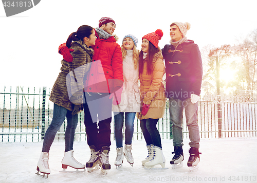 Image of happy friends ice skating on rink outdoors