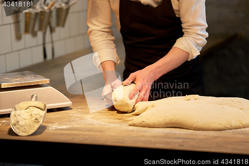 Image of baker portioning dough with bench cutter at bakery