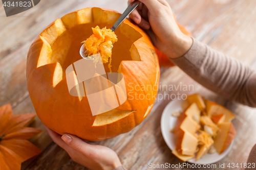 Image of close up of woman carving halloween pumpkin