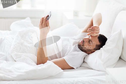 Image of young man with smartphone in bed in morning