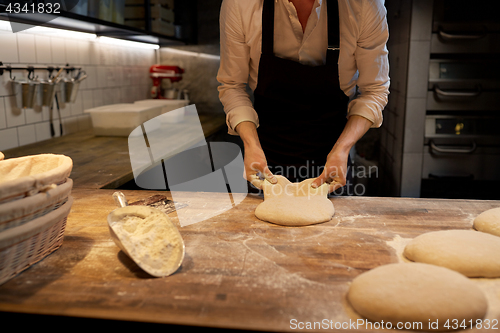 Image of baker portioning dough with bench cutter at bakery