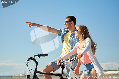 Image of happy young couple riding bicycles at seaside