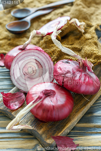Image of Sweet red onions on an old wooden board.