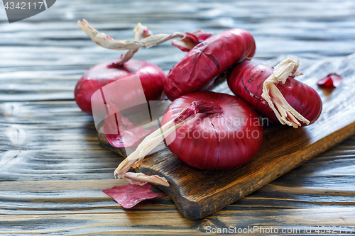 Image of Sweet red onions on an old wooden board.