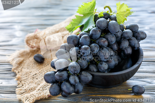 Image of Delicious black grapes in a wooden bowl.