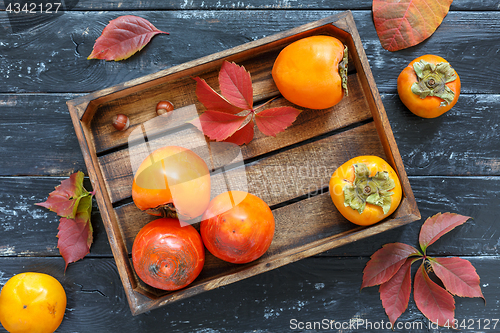 Image of Juicy ripe persimmon in a wooden box.