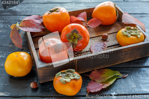 Image of Juicy ripe persimmon in a wooden box.