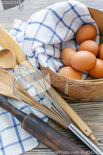 Image of Brown eggs in old sieve,rolling pin,whisk and spoon.