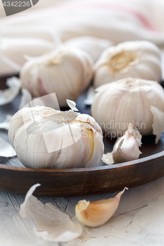 Image of Garlic, cloves and peel on a wooden dish.