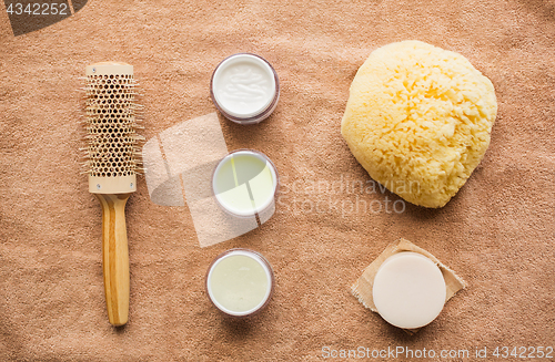 Image of hair brush, cream, sponge, soap bar and bath towel