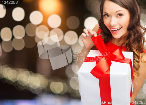 Image of smiling woman in red dress with christmas gift box