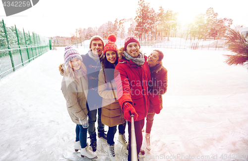 Image of happy friends with smartphone on ice skating rink