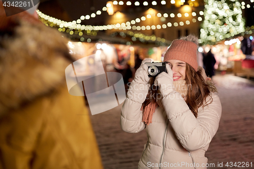 Image of woman with camera photographing man at christmas