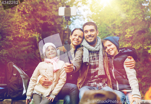Image of family with smartphone taking selfie near campfire