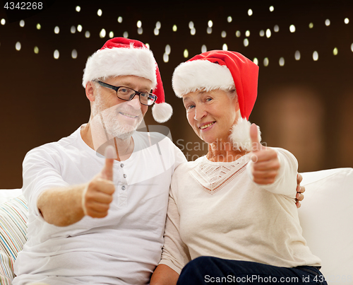 Image of happy senior couple in santa hats for christmas