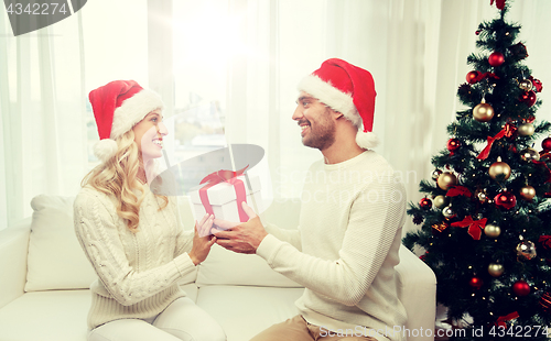 Image of happy couple at home with christmas gift box