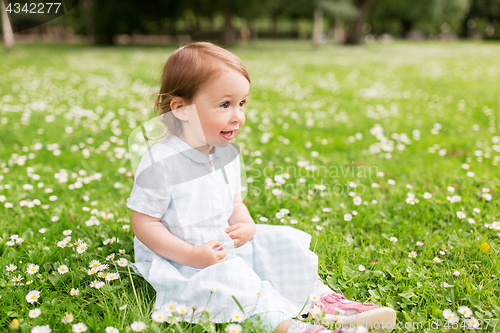 Image of happy baby girl on green summer field