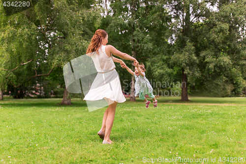Image of happy mother playing with baby girl at summer park