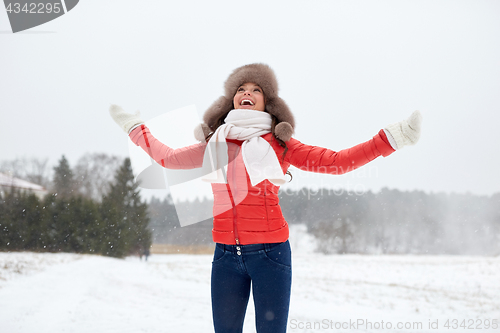 Image of happy woman in winter fur hat having fun outdoors