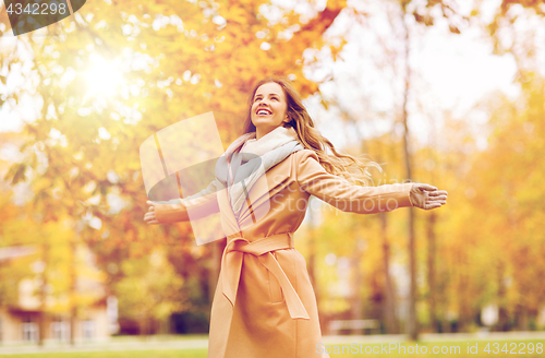 Image of beautiful happy young woman walking in autumn park