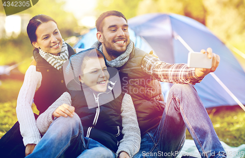 Image of family with smartphone taking selfie at campsite