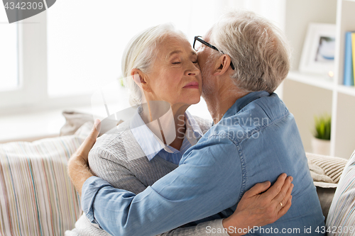 Image of happy senior couple hugging at home