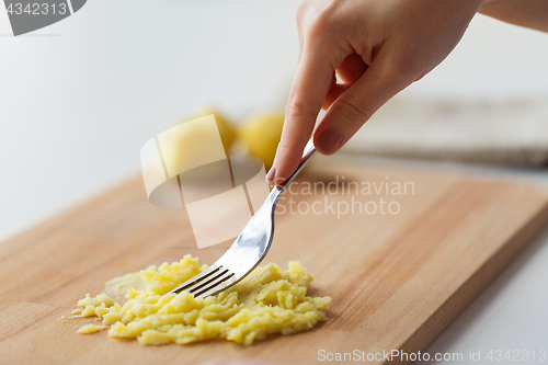 Image of hand with fork making mashed potato on board