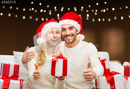 Image of happy couple with christmas gifts and thumbs up