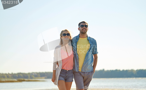 Image of happy couple in sunglasses hugging on summer beach