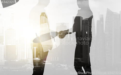 Image of business people shaking hands over city background